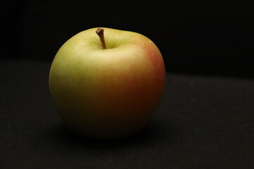 黒い背景に置かれたりんごのクローズアップ（光と影が強調された静物写真）