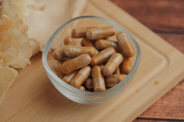 Herbal supplements in a glass bowl and mushroom on a table 