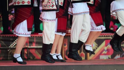 Traditional folk dancers performing traditional step dance on stage, celebrating their culture through traditional movements. Wearing vibrant Moldavian costumes