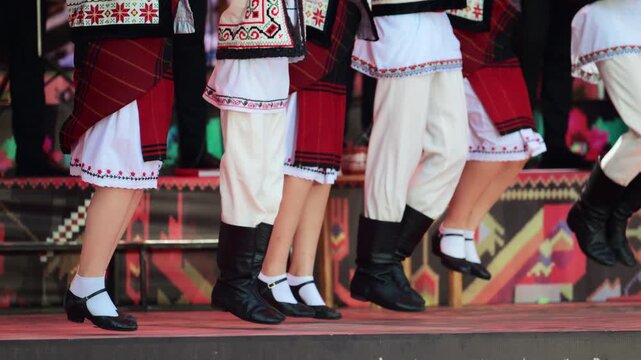 Traditional folk dancers performing traditional step dance on stage, celebrating their culture through traditional movements. Wearing vibrant Moldavian costumes