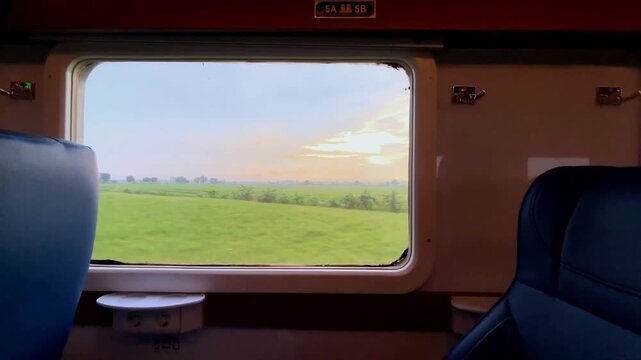 View from the train window. Beautiful view from the window of a long-distance train, with green rice fields stretching out and residential areas on the edge of the rice fields during a light rain.