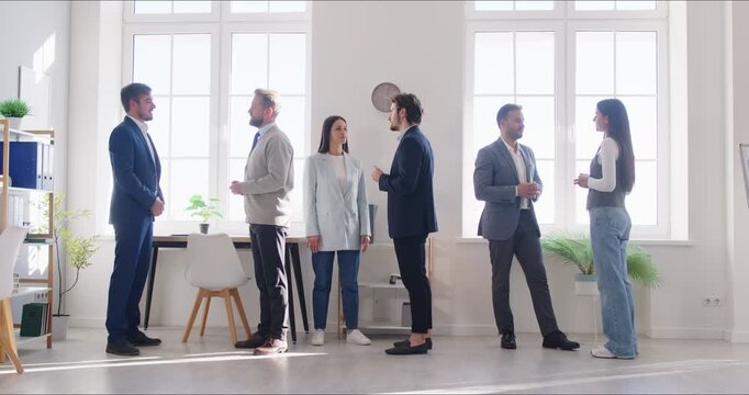 Full length video of young business people men and women chatting after meeting. Company employees or group of staff talking in modern office or conference room discussing work project. 4k video.