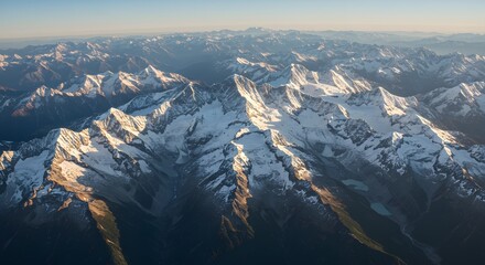 Aerial view of majestic snow-capped mountain range, bathed in warm sunlight