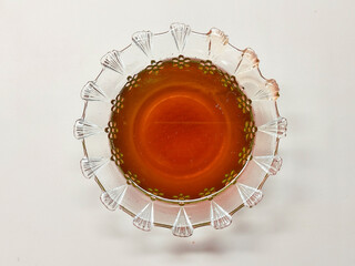 A beautiful ornate glass bowl filled with pure liquid honey, showcasing the natural sweetness and golden amber color of this healthy food from a top view