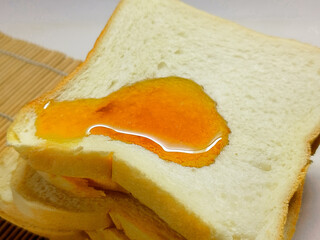 Close-up shot of a delicious, golden honey dripping onto a stack of fluffy, white bread slices, perfect for breakfast or a sweet snack