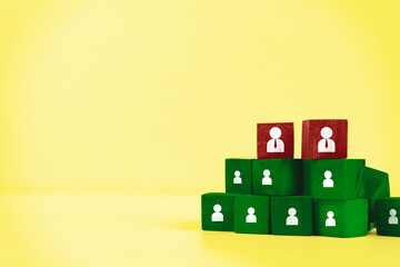 Organizational Hierarchy Concept - Wooden Blocks with People Icons on Yellow Background.