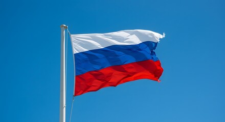 A tricolor flag of three horizontal bands waving against a clear blue sky