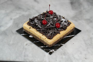 Black caramel salt cake with cherries, marble backdrop