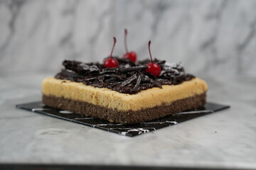 Black caramel salt cake with cherries, marble backdrop