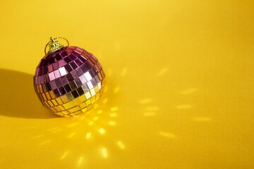 Sparkling Disco Ball on Yellow Background. Retro Party Celebration and Decorations for Christmas.