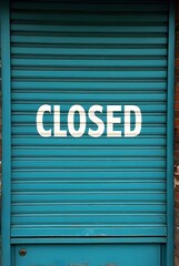 Teal metal roller shutter door with strong horizontal lines prominently displays the white CLOSED text, vertical composition. The distressed surface and brick framing emphasize this urban scene.