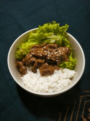 Fried beef or fried empal menu with sesame seeds sprinkled on it, white rice as a source of carbohydrates and fresh green lettuce.