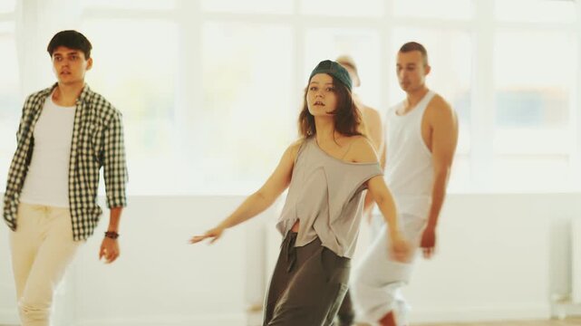 Young man standing performs basic hip hop movements in front of group of students. Developing precise movements, rehearsing arc elements, nae nae moving 