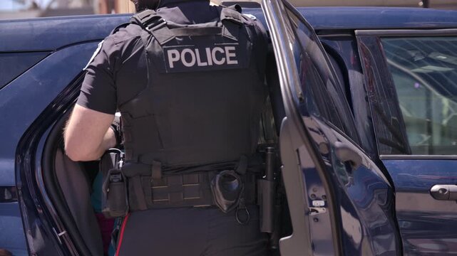 Police officer with suspect in the back of patrol car