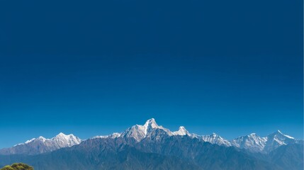 A vast mountain range with snow-capped peaks under a clear blue sky, wide-angle view capturing majestic landscape.