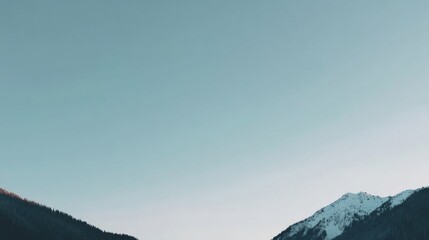 Serene mountainous landscape with snow-capped peaks, lush greenery, and a pale clear sky,