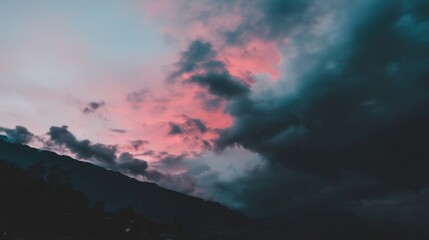 Dramatic sunrise or sunset landscape with pink purple blue sky reflecting on dense clouds rolling hills silhouette moody