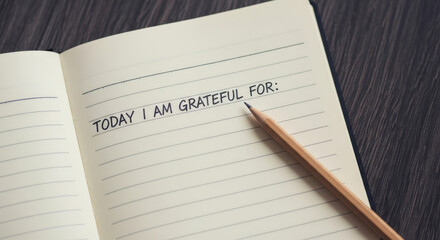 A notebook open to a page that says today i am grateful for with a pencil on the page