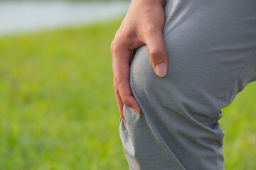 Athlete experiencing knee pain on grassy terrain—likely due to hamstring strain or joint...