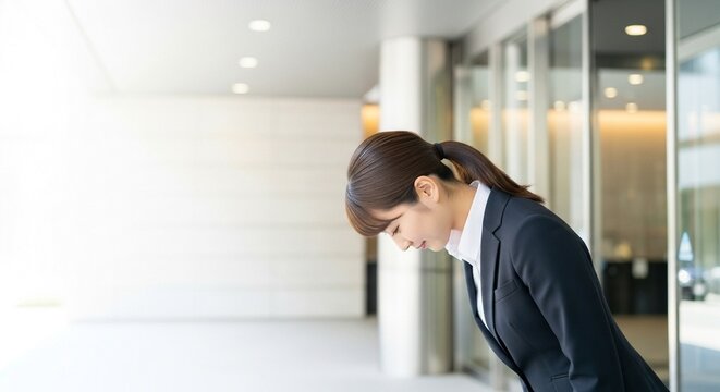 企業のおもてなし：エントランスでお辞儀する日本人女性社員の接客マナー（お見送り・お出迎え）