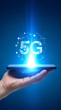 A hand holds a smartphone projecting a glowing 5G symbol with network connections and light on a blue background