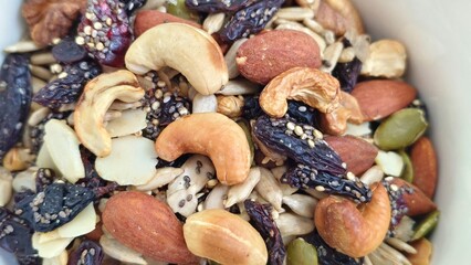 Healthy mix of nuts, seeds, and dried fruits served in a white bowl, perfect for a nutritious snack or breakfast topping.