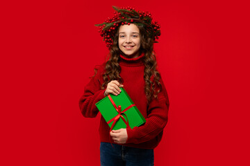 Teen girl in a Christmas berry wreath holding a green gift box