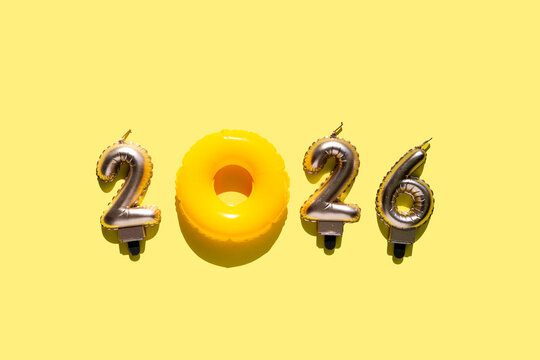 Playful “2026” numbers composition where an orange inflatable swim ring replaces the zero, on a warm yellow background. Ideal for summer, travel, or holiday projects