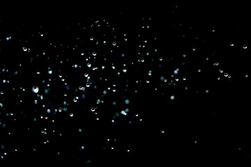 Macro shot of shimmering water droplets against a dark background.