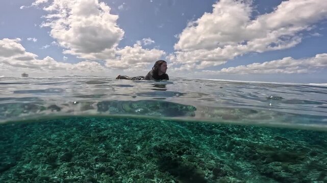 Surfer waiting in crystal-clear water at Cloudbreak, Fiji. Stunning shot with view above and below the surface, showcasing reef, ocean clarity, and tropical paradise vibes.