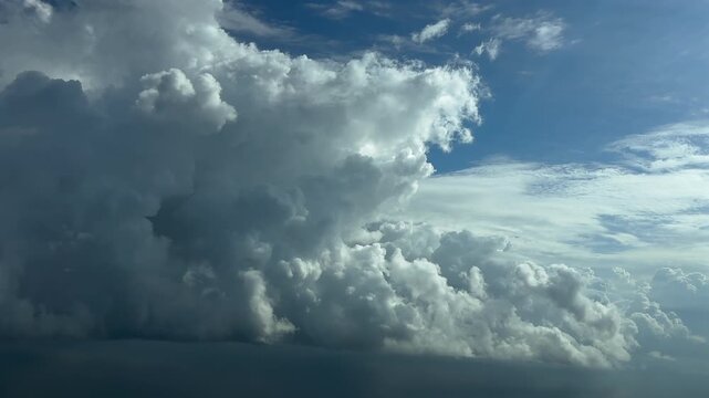 An immersive pilot&rsquo;s perspective from the cockpit of a jet airplane flying near towering and threatening Cumulonimbus storm clouds in a bright blue sky.