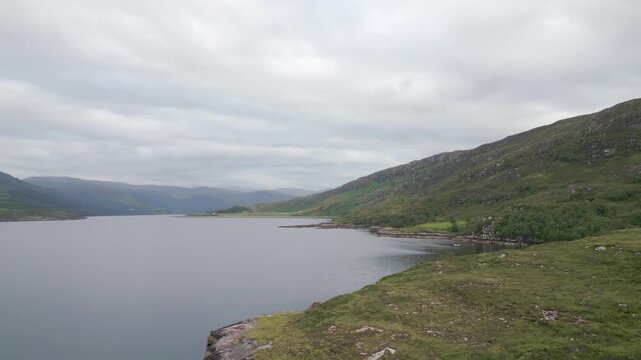 Aerial view along a calm sea loch with green slopes and rocky headlands near Ullapool