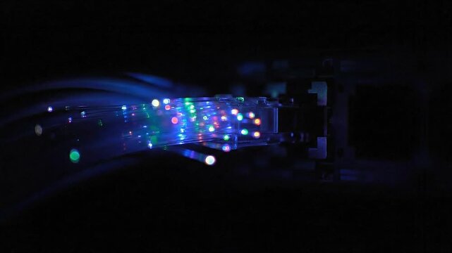 Abstract View of Illuminated Fiber Optic Cables Against Dark Background with Shimmering Blue Green and Red Light Particles