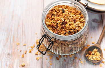 Granola breakfast cereal in glass jar with spoon