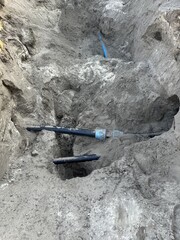 A pit with utility and water pipes in excavated sandy soil, ongoing industrial work