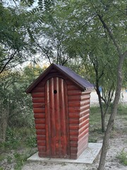 Wooden public toilet on the beach among the trees