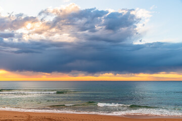 Winter sunrise by the sea shore with rain clouds