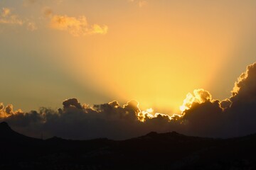 A spectacular sunset or sunrise scene with intense golden crepuscular rays bursting from behind...