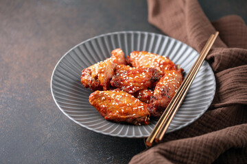 Chicken wings with teriyaki sauce and sesame seeds in a bowl on the table.