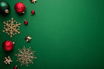 Merry Christmas and Happy Holidays greeting card, frame, banner. New Year. Noel. Red, golden Christmas ornaments on green background top view. Winter xmas holiday festive theme. Flat lay	
