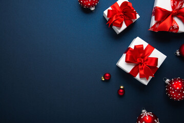 Merry Christmas and Happy Holidays greeting card, frame, banner. New Year. Red and white Christmas decorations and gifts on blue background top view. Winter xmas holiday celebration theme.