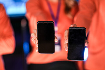 Two app developers showcase their new product on mobile phones. The blank screens provide a perfect template for marketing agencies to add a custom user interface for a new app launch.