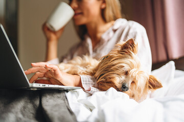 Woman enjoys quiet morning with coffee and dog while working on a laptop at home