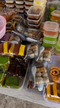 Various traditional Indonesian snacks in plastic packaging, including meatball, sponge cake, jelly pudding, and layered talam cake. street food