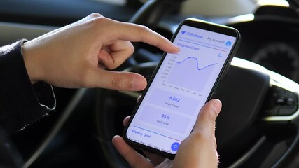 A man's hands in a parked car interact with a comprehensive health application, tapping on activity graphs to view detailed metrics about steps, sleep, and other wellness data.  - Powered by Adobe