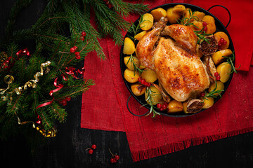Roasted chicken with potatoes and Christmas decoration. Baked chicken or turkey. Table setting. Top view, flat lay
