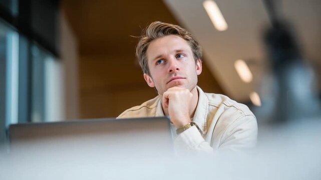 Thoughtful Contemplation: A focused individual, engaged in deep thought with a laptop in front of him, showcasing an expression of concentrated contemplation.