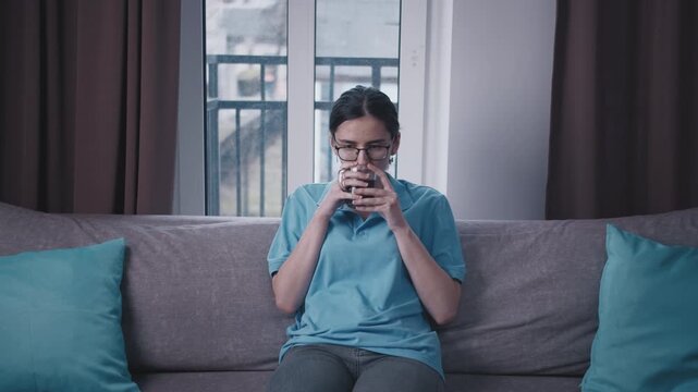 Teenage Girl Sitting on the Couch at Home in the Evening, Drinking Tea and Reflecting on Positive Memories