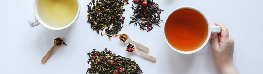 Assortment of tea types with cups and loose leaves on a white background
