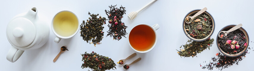 Assortment of teas with teapot, cups, and wooden spoons on white background